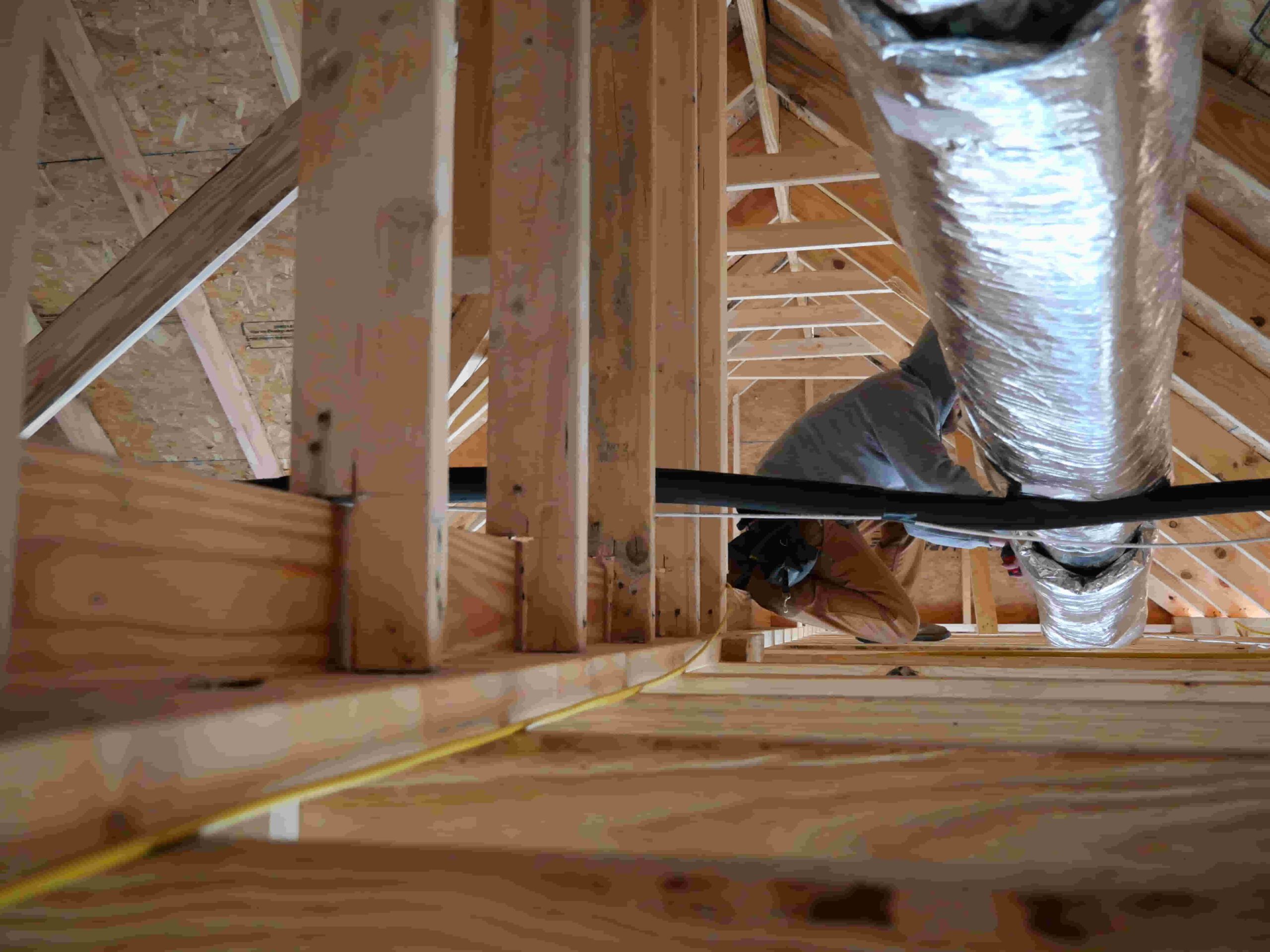 Burris Heat & Air worker installing a pipe on a roof in an attic.