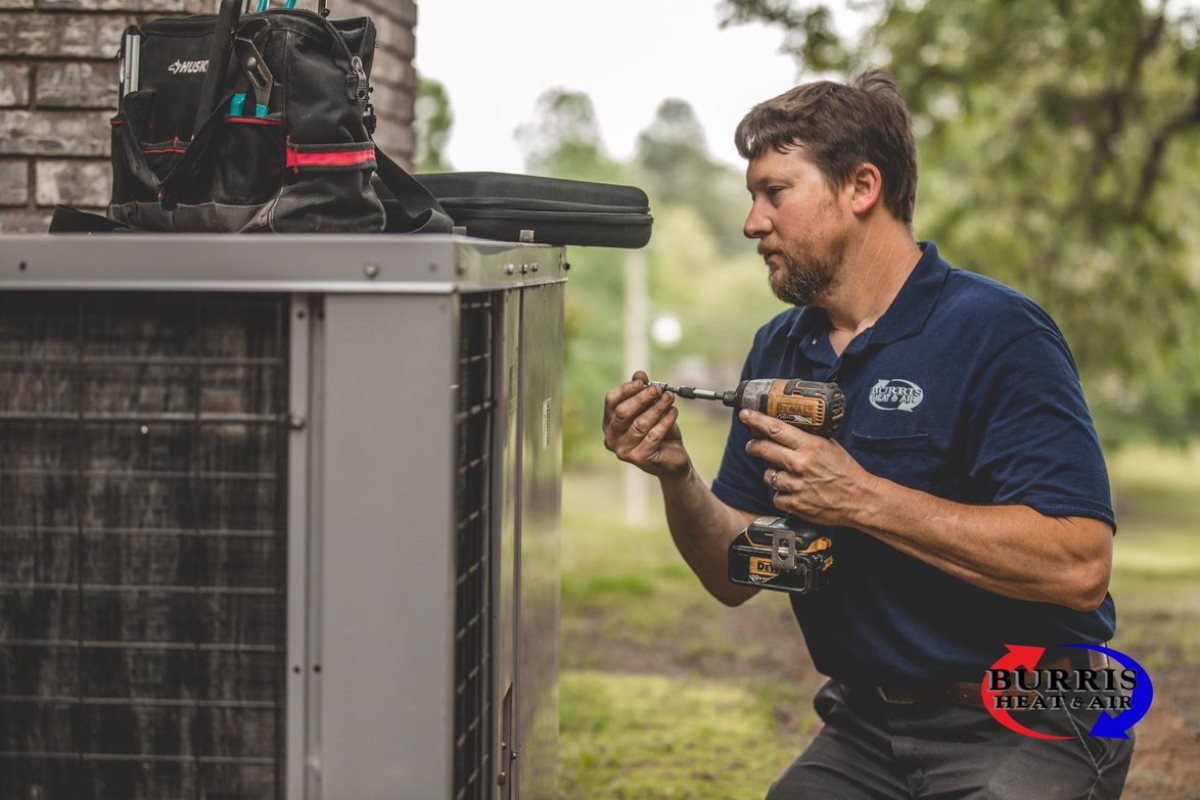 HVAC technician installing an AC unit with an electric drill.